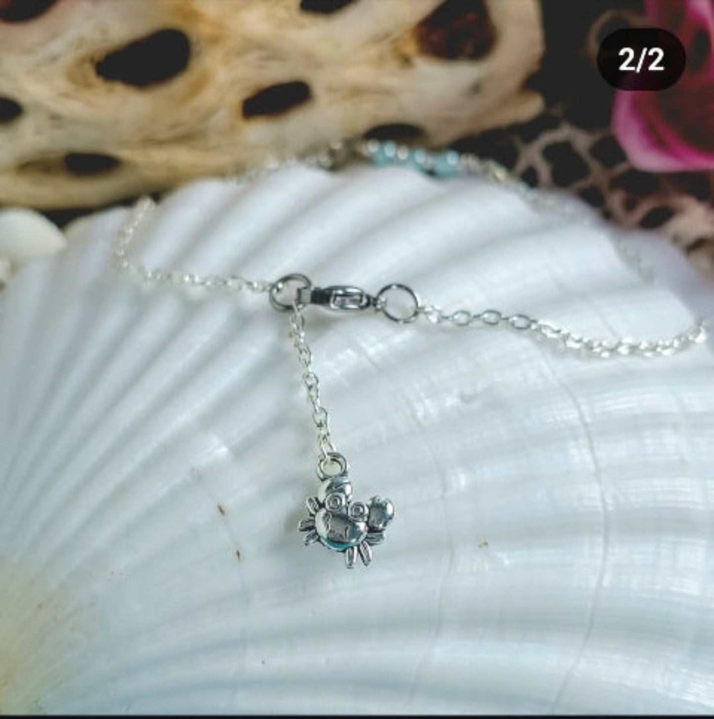 A close-up view of the clasp and extender chain of a silver anklet featuring a tiny silver-plated crab charm.