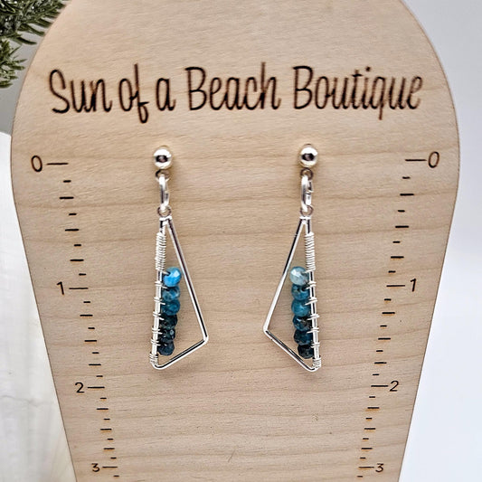 Silver and blue triangle earrings on a display stand. "Sun of a Beach Boutique" is written at the top.