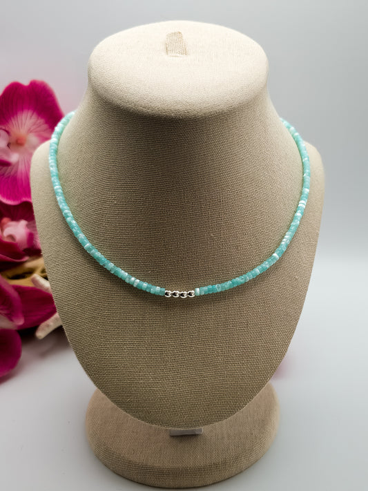 Turquoise Mother of pearl and silver beaded choker necklace with stainless steel extender chain and stainless steel lobster claw clasp on a beige neck form with flowers and driftwood background for staging. 